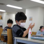Child, wearing a protective face mask, following an outbreak of coronavirus, uses hand sanitizer at “Stella Kids”, daycare center in Tokyo